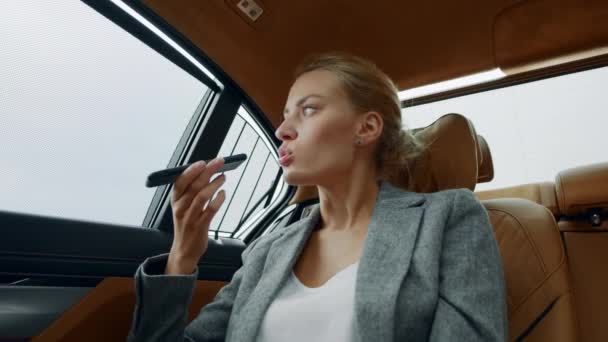 Lähikuva vakava liiketoiminnan nainen tallentaa ääniviestin matkapuhelimeen autossa. - Materiaali, video