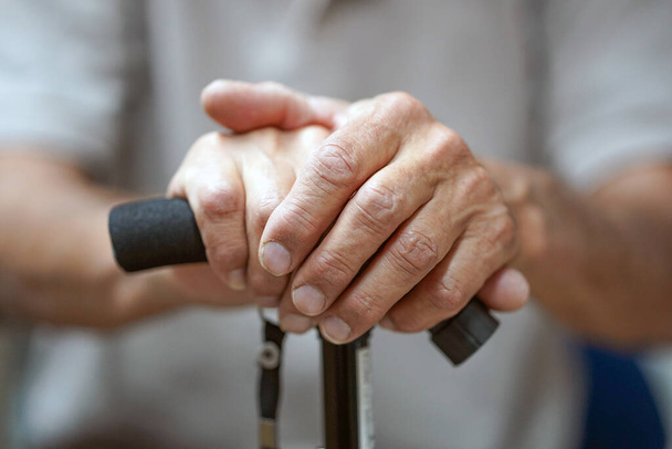 Hand van een oude man met een stok. Senior Man Holding Cane. Close-up van oude man handen op wandelstok. - Foto, afbeelding