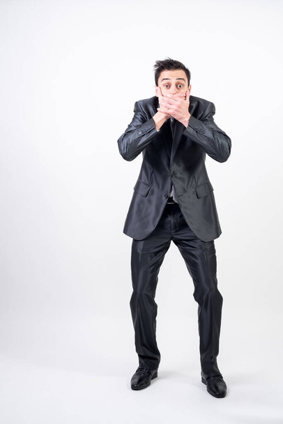 Man in suit covering his mouth with his hands because he said something unintentionally. on white background, full body - Photo, Image