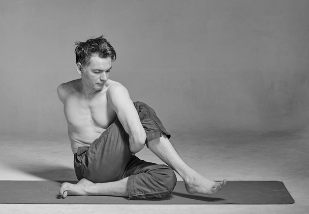 Young handsome man performing yoga exercises - Φωτογραφία, εικόνα