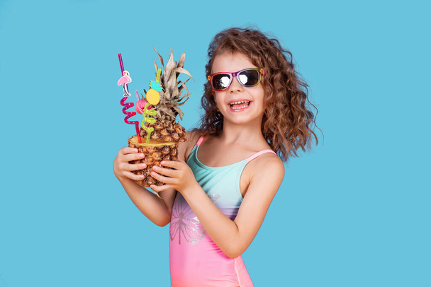 Beautiful girl in colorful swimsuit and sunglasses holding pineapple cocktail - Foto, Imagem