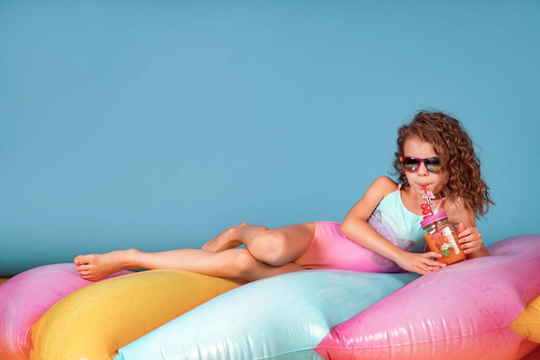Hermosa chica en traje de baño colorido y gafas de sol celebración de cóctel de piña
 - Foto, imagen