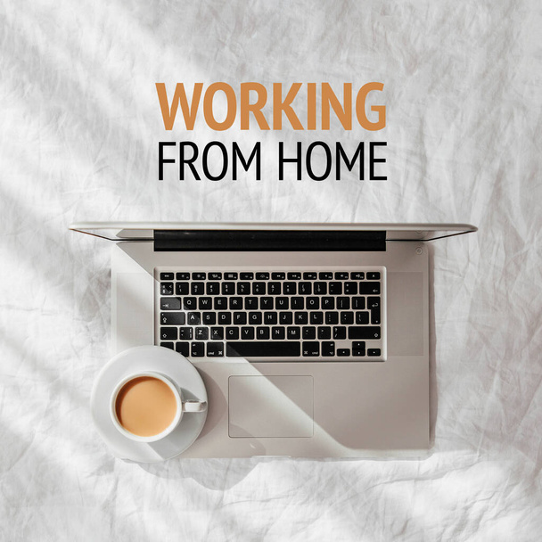 Laptop and cup of coffee on white bed. Work at home concept. Morning light  - Фото, изображение