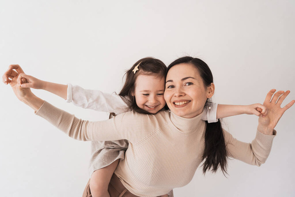 A happy mom plays with her daughter. Mom rolls the baby on her back. Family lifestyle at home. Smiling mom and daughter enjoy each other. - Photo, image