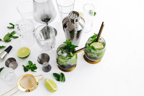 Cocktail with lime, mint and ice and  bar accessories on. Summer drinks. - Foto, imagen