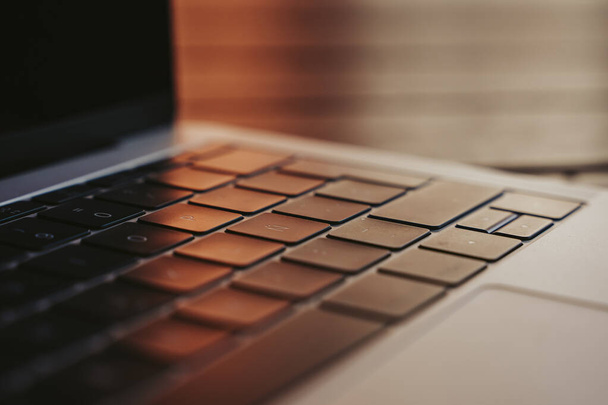 Sleutels van een laptop in een buitenlucht op een houten tafel bij zonsondergang. - Foto, afbeelding