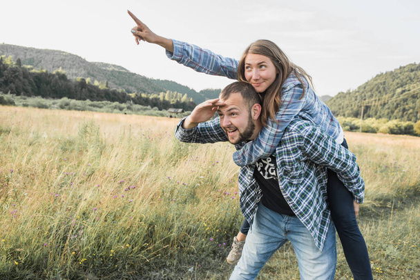 Portrait of nice sweet, loving two people, European couple, bearded guy and pretty girl wearing casual checkered shirt. Happy honeymoon vacation in wild forest, mountains  - Photo, image