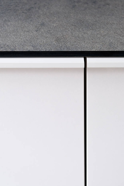 Lähikuva keittiön valkoinen kaappi ovi ja harmaa työtaso
 - Valokuva, kuva