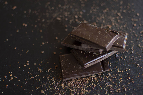 Pezzi di cioccolato fondente amaro su sfondo scuro
. - Foto, immagini