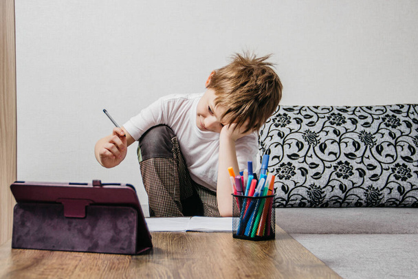 Un niño se sienta en casa aislado y aprende en línea
 - Foto, imagen