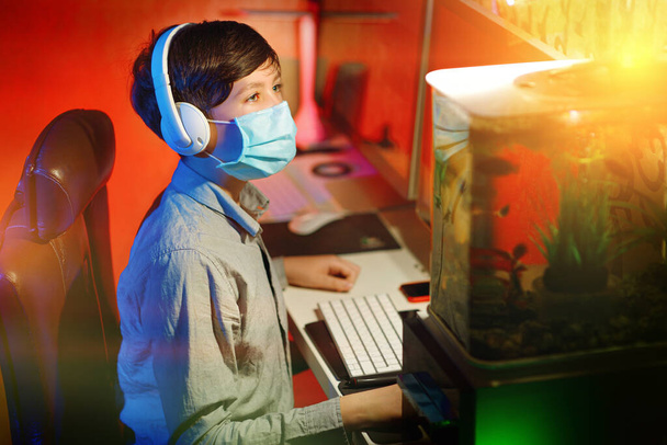 Jeune garçon étudiant à la maison avec des cours en ligne pendant la quarantaine du coronavirus. Concept d'enseignement à distance
. - Photo, image