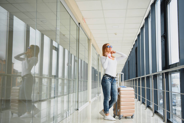 Girl traveler walking with carrying hold suitcase in the airport. Tourist Concept. Woman walks through airport terminal with luggage. travel concept - 写真・画像
