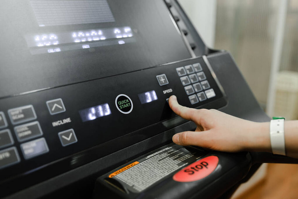 Get ready to run- hand pushes the green start button on a treadmill in a home gym, hand click stop button im treadmill - 写真・画像
