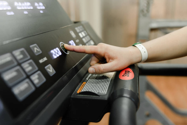 Get ready to run- hand pushes the green start button on a treadmill in a home gym, hand click stop button im treadmill - 写真・画像