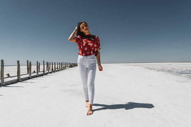 beautiful girl of European appearance cute smiles on a warm summer day,a young girl stands in the middle of an empty salt lake,fashionable woman walks along the road,beautiful girl in the desert - Foto, imagen