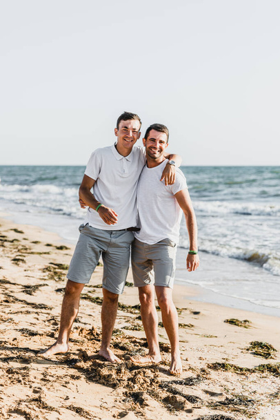 best friends cuddling on the beach,vacation with a friend at sea,fooling around with a friend,friend holds friend in his arms,walk along the beach,two nice guys,nice and lovely guys - Photo, Image