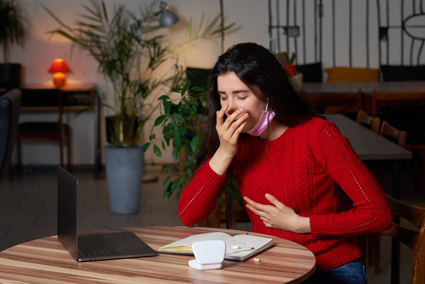 mujer enferma con pastillas y termómetro en una mesa trabajando en una computadora portátil desde casa en el aislamiento de cuarentena
. - Foto, Imagen