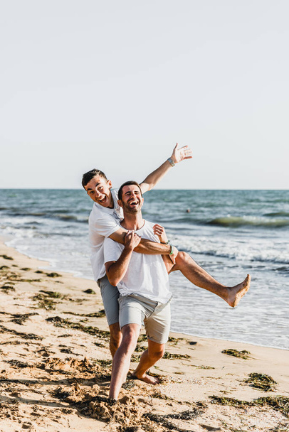melhores amigos abraçando na praia, férias com um amigo no mar, brincando com um amigo, amigo segura amigo em seus braços, caminhar ao longo da praia, dois caras legais, caras agradáveis e adoráveis
 - Foto, Imagem