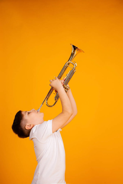 A boy plays the trumpet. Beautiful teenager boy plays trumpet musical instrument - Zdjęcie, obraz