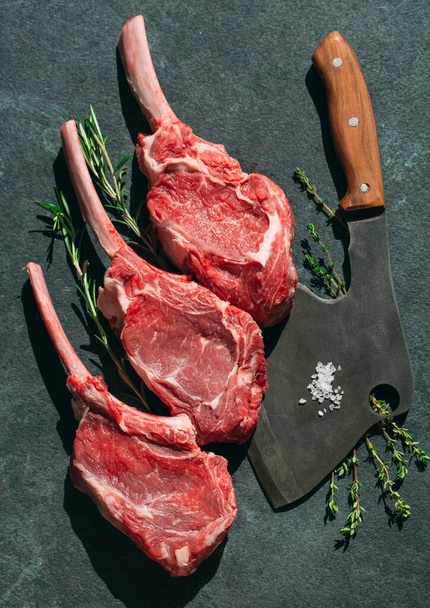 Raw steak with a meat cleaver on a dark stone background - Foto, imagen