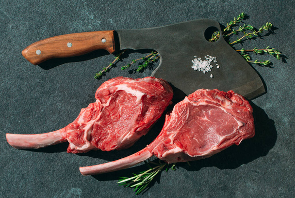 Raw steak with a meat cleaver on a dark stone background - Фото, зображення