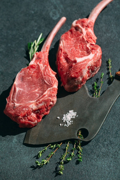 Raw steak with a meat cleaver on a dark stone background - Photo, image
