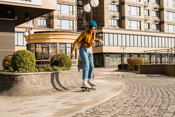 Skateboarding at city. Female, enjoyment. Hipster girl riding skate board. Ride, style. Extreme sport and emotions concept. Alternative lifestyle. Woman skateboarder skateboarding at city. - Photo, Image