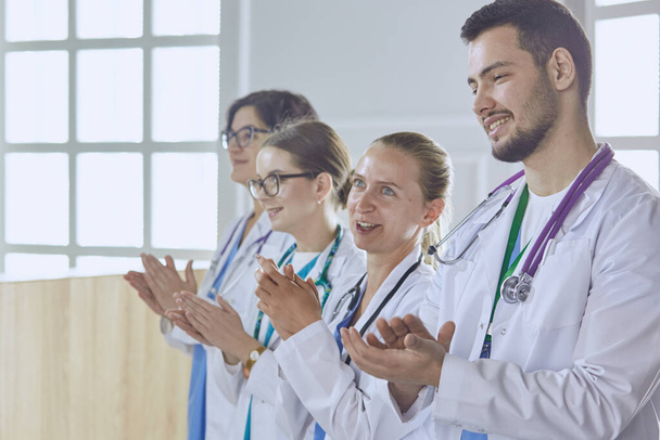 Gelukkig medisch team bestaande uit mannelijke en vrouwelijke artsen brede glimlach en geven een duim omhoog van succes en hoop - Foto, afbeelding
