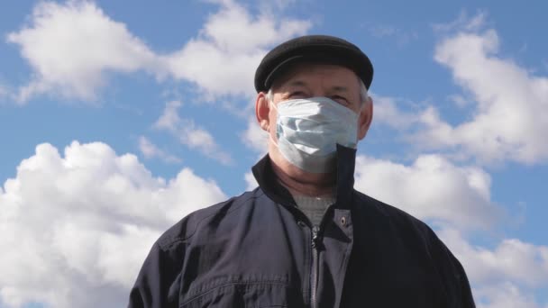Een oudere man op straat met een medisch masker. Pandemisch coronavirus. De man draagt een beschermend masker op straat. gezondheidsconcept, quarantaine van het coronavirus N1H1, virusbescherming. risico op infectie. - Video