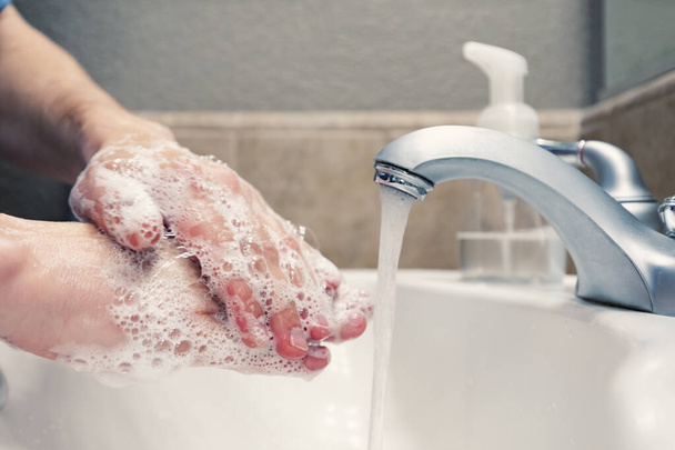Se laver les mains avec du savon et de l'eau dans l'évier de salle de bain, protection contre les virus de la grippe à coronavirus covid-19, hygiène pour rester en bonne santé
 - Photo, image