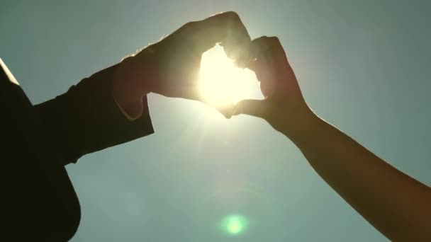 sun in hand. Silhouette of a loving couple making a heart symbol with their hands opposite the sun on the horizon. teamwork of loving couple. Wedding day celebration - Footage, Video