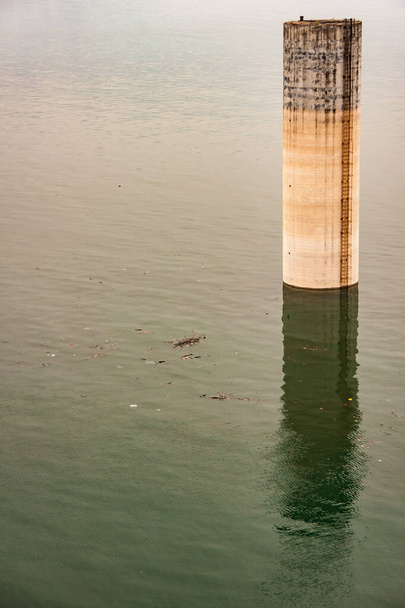 Zapora Three Gorges, Chiny - 6 maja 2010: Jangcy. Poranek, zbliżenie 1 wysokiej brązowej betonowej wieży ochronnej wystającej z zielonej wody z cieniem. - Zdjęcie, obraz