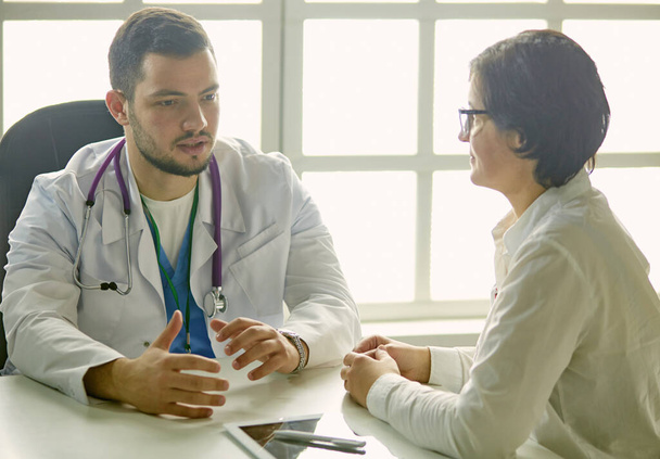 Giovane medico che parla con un paziente in ufficio
 - Foto, immagini