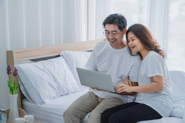 Una pareja asiática mayor está en casa felizmente en la mañana del feriado y está teniendo una videollamada. Las compras en línea se pueden hacer fácil y convenientemente con una sola tarjeta de crédito
. - Foto, imagen