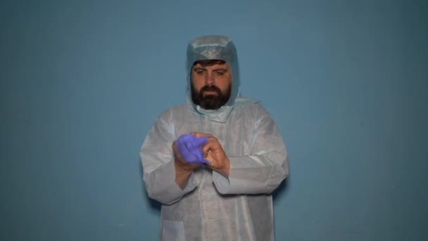 Vousatý lékař si oblékne ochranný lékařský oblek v laboratoři během pandemie koronaviru Covid-19. - Záběry, video