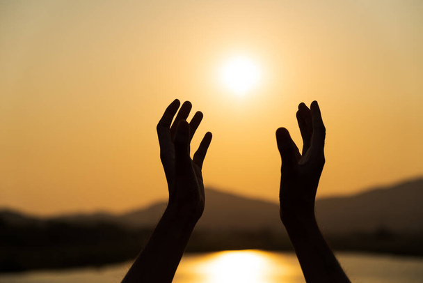 Крупным планом женщина руками молится за благословение от Бога на фоне заката. Надежда
. - Фото, изображение