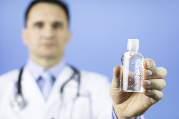 Medical specialist in uniform with alcohol gel in hand. Focus on antiseptic - 写真・画像