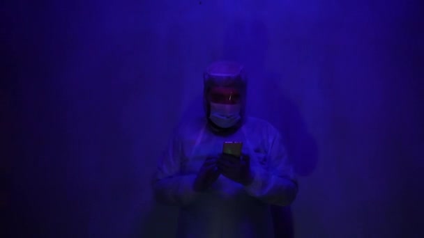 Baard arts in een beschermende medische pak tijdens angst in het laboratorium. Ongeval in het laboratorium tijdens de coronaviruspandemie. Het licht van de sirene is blauw-rood. Het effect van slechte verlichting in de ruimte. - Video