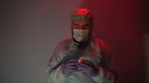 Laboratuvarda anksiyete sırasında koruyucu giysi giymiş sakallı bir doktor. Coronavirus salgını sırasında laboratuvarda bir kaza olmuş. Sirenin ışığı mavi-kırmızıdır. Odadaki kötü ışığın etkisi.. - Video, Çekim