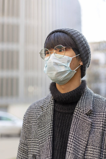 Asian young man in protective mask against covid-19. Chinese coronavirus concept - Photo, Image