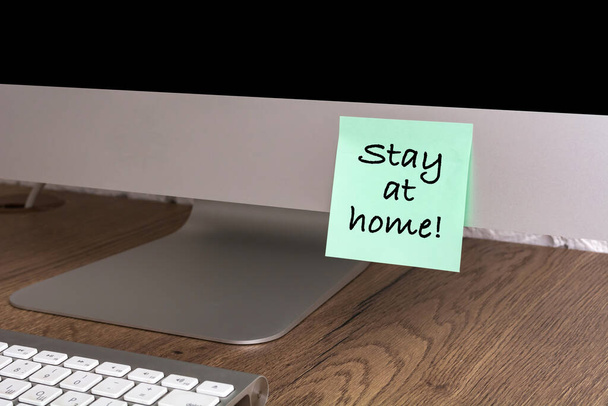 Computer with a sticker with the text Stay at home. Concept about quarantine and remote work. - Photo, image