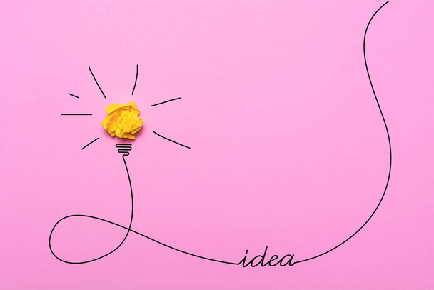 砕いた紙の創造的なアイデア.ピンクの背景に燃える電球。教育理念. - 写真・画像