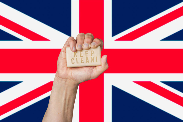 Caucásico mano masculina celebración de jabón con frase: Mantener limpio, contra fondo de la bandera británica
 - Foto, Imagen