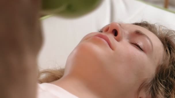 Uma mulher está em uma cama de massagem com rolos de jade
. - Filmagem, Vídeo