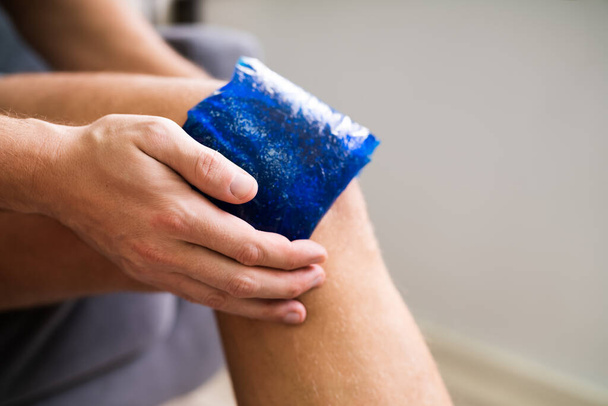 Midsection Of Man Holding Cool Gel Pack On Knee For Pain Relief Over White Background - Zdjęcie, obraz