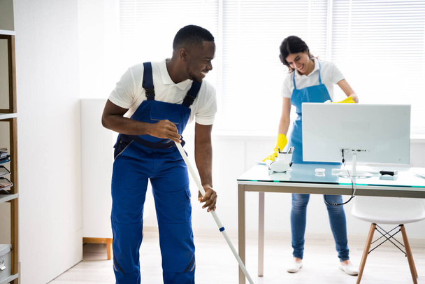 Young Male And Female Cleaners Cleaning Office - Foto, Imagen