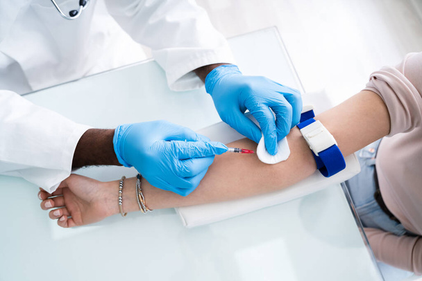 Lähikuva nainen lääkäri pistämällä mies potilaan ruisku kerätä verinäyte
 - Valokuva, kuva