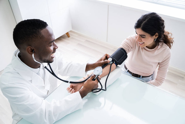 Close-up Of Doctor Measuring Patients Blood Pressure With Stethoscope - Foto, immagini
