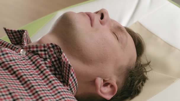 Un homme se couche sur un lit de massage avec des rouleaux de jade
. - Séquence, vidéo