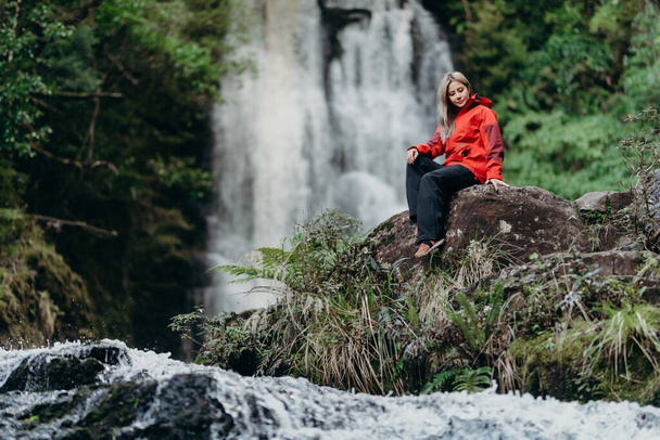 Beautiful woman hiker standing at front of waterfalls and looking away. Asian female on hike in nature. - Φωτογραφία, εικόνα